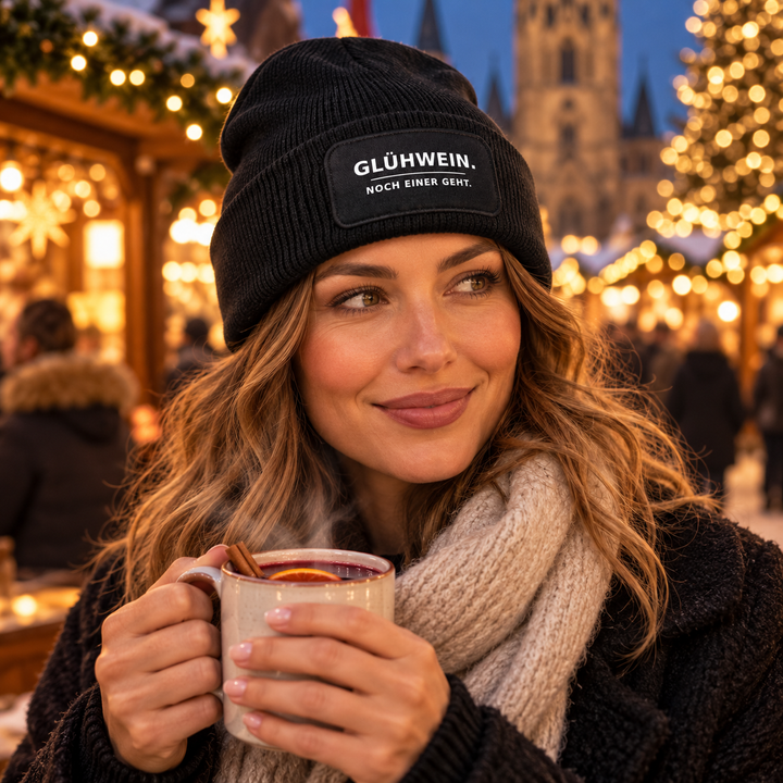 Frau mit Glühwein trägt die Mütze GLÜHWEIN. NOCH EINER GEHT.