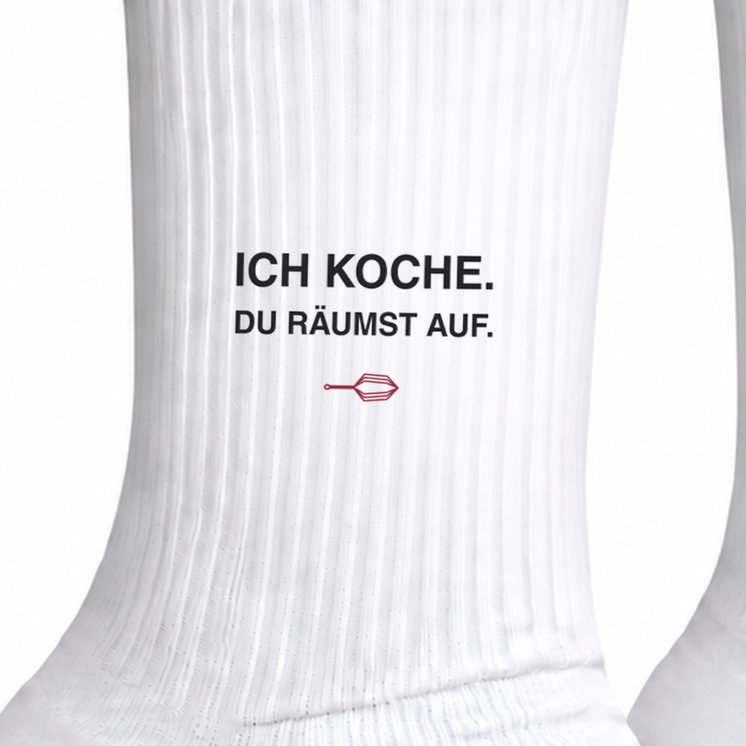 Nahaufnahme des Aufdrucks Ich koche Du räumst auf auf weißer Socke