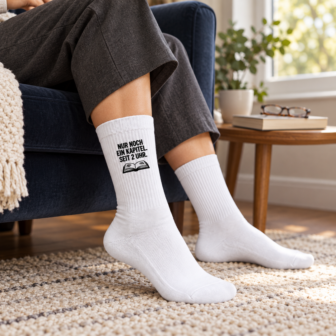 Leserin trägt weiße Bücherfan-Socken mit kompaktem Aufdruck im Sessel