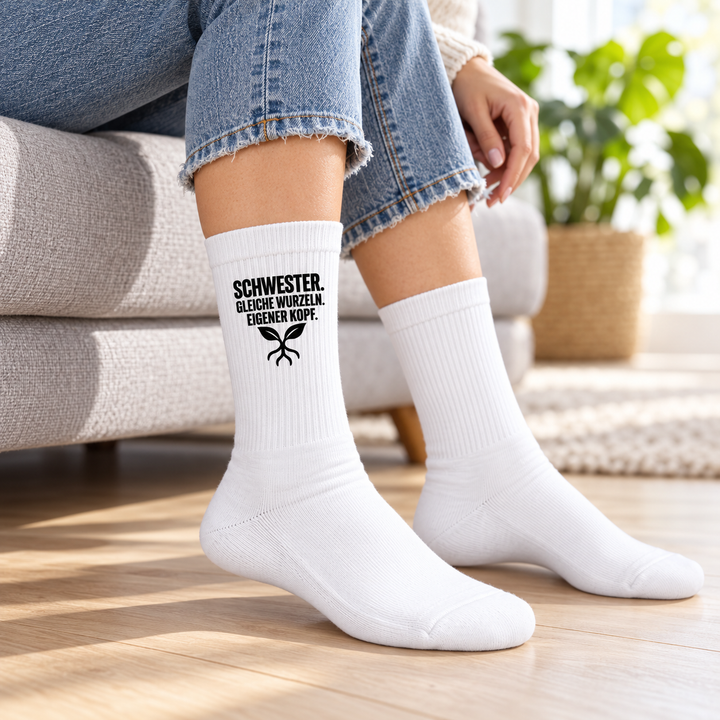 Frau trägt weiße Schwester-Socken mit schwarzem Motiv außen am Schaft auf einem Sofa