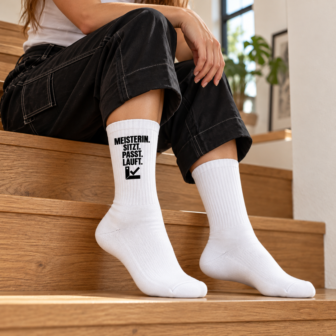 Weiße Handwerkerin-Socken im Alltag auf Holzstufen, Motiv außen am Schaft