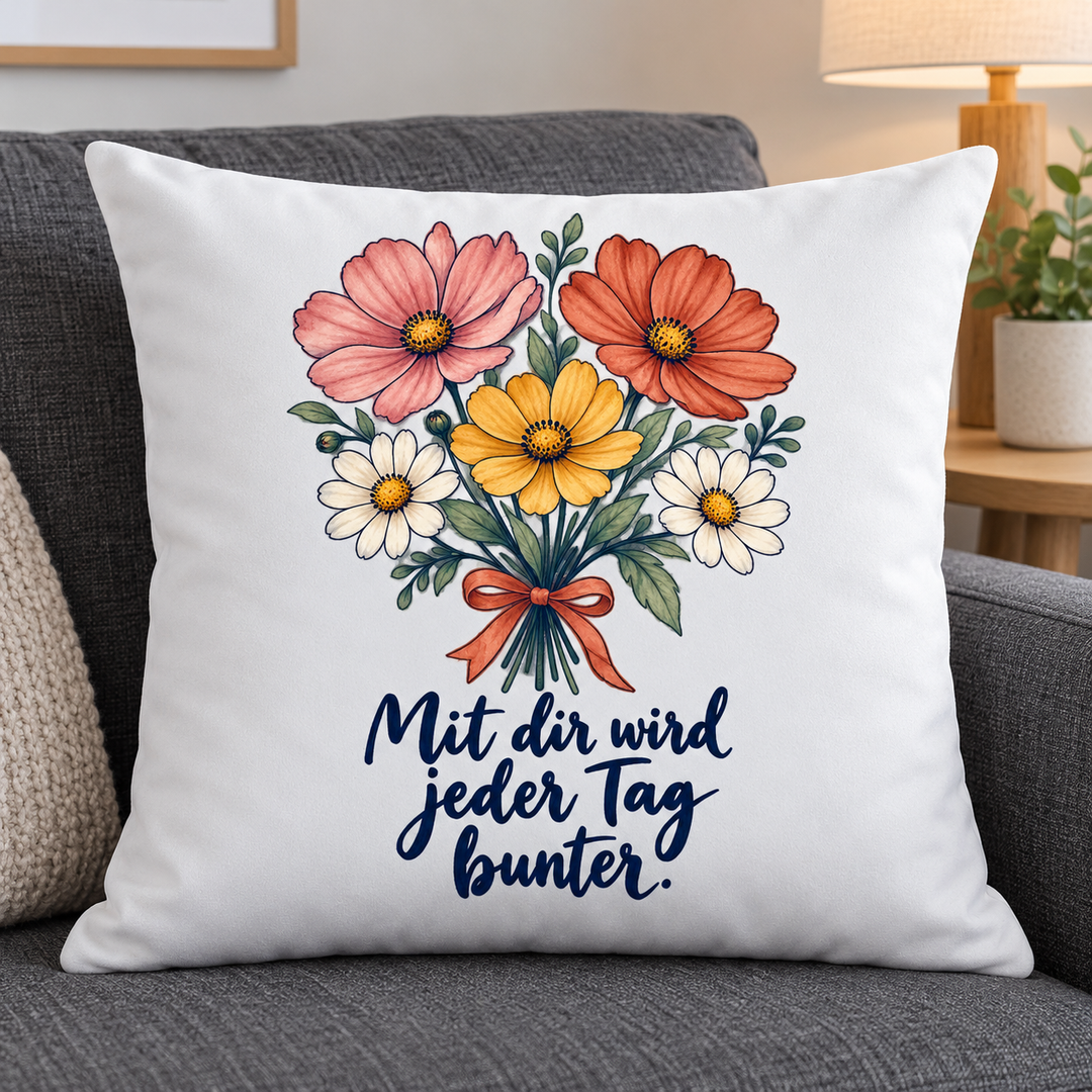 Weißes Kissen mit Blumenstrauß und liebevollem Spruch auf grauem Sofa