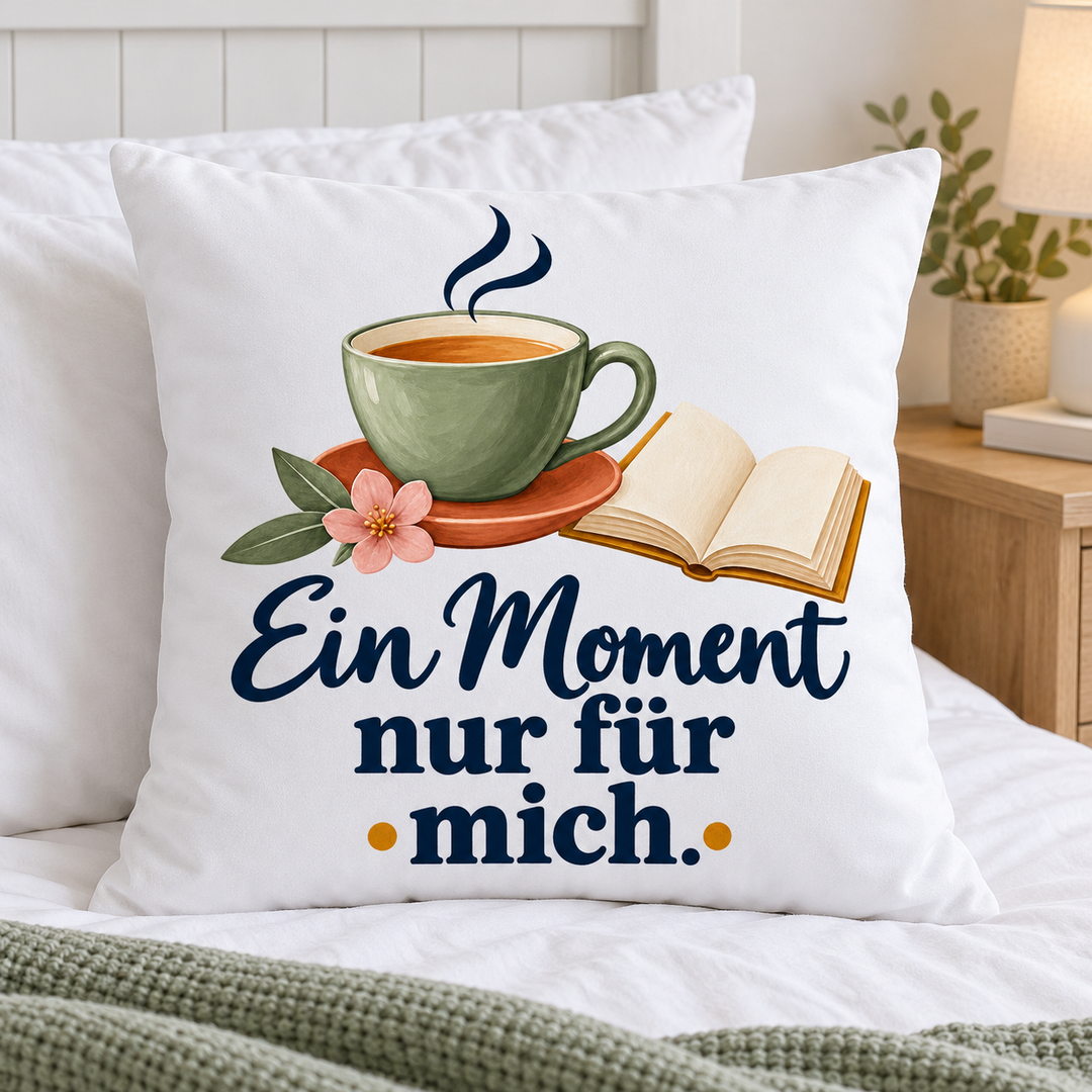Weißes Auszeit-Kissen mit Tasse und Buch auf einem gemütlichen Bett