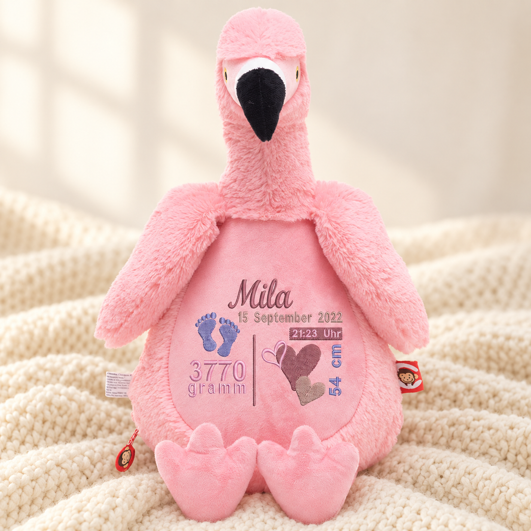 Personalisiertes Kuscheltier Flamingo mit Name – Beispiel Mila auf cremefarbener Decke