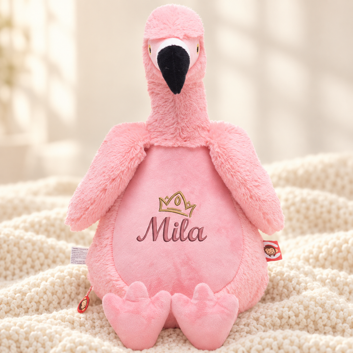 Personalisiertes Kuscheltier Flamingo mit Name &amp; Krone – Beispiel Mila auf cremefarbener Decke