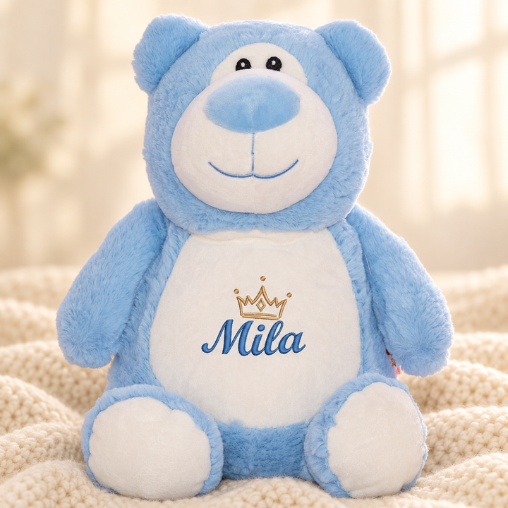Personalisiertes Kuscheltier Bär Blau mit Name &amp; Krone – Beispiel Mila auf cremefarbener Decke