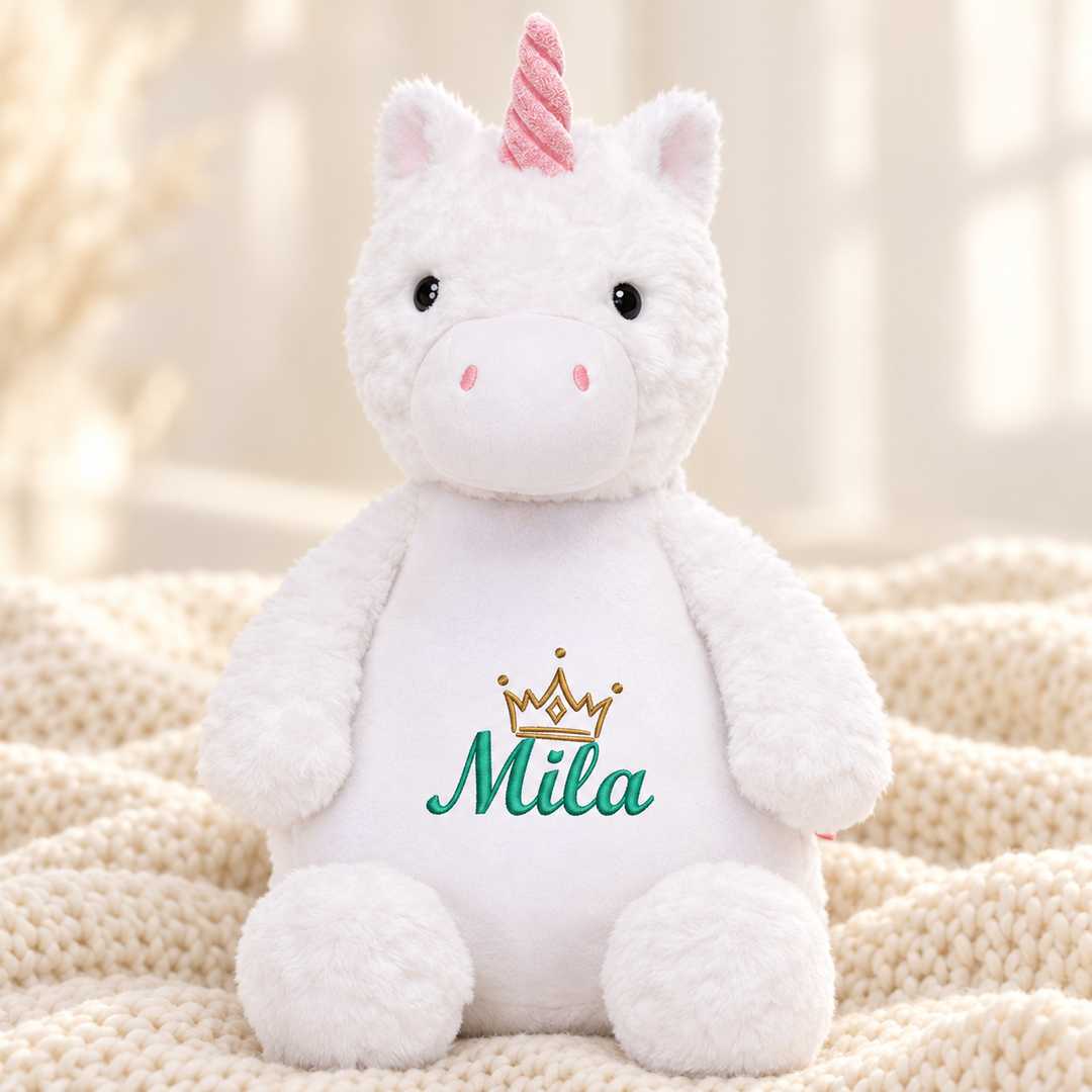 Personalisiertes Kuscheltier Einhorn mit Name &amp; Krone – Beispiel Mila auf cremefarbener Decke