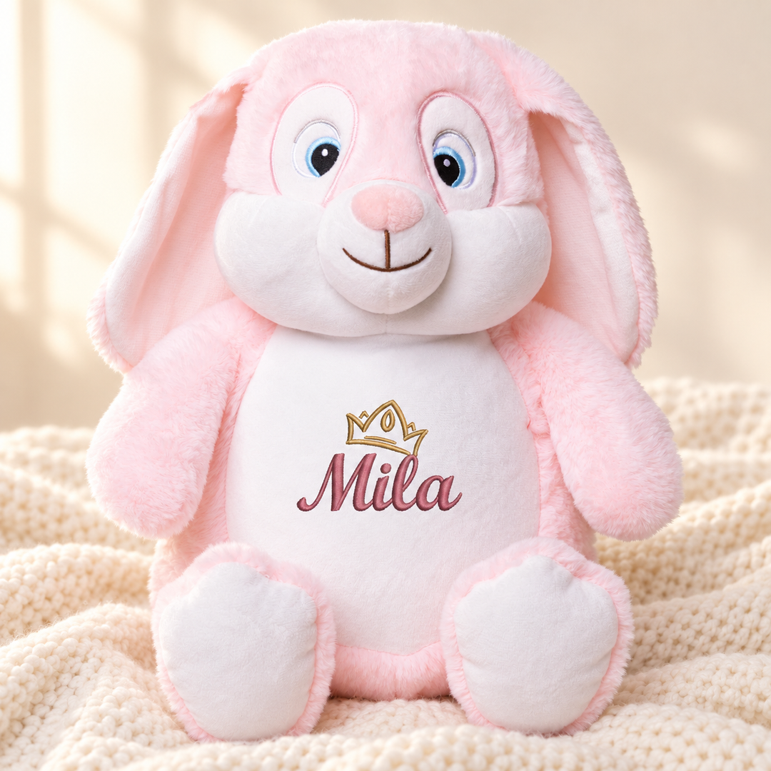 Personalisiertes Kuscheltier Hase Rosa mit Name & Krone – Beispiel Mila auf cremefarbener Decke