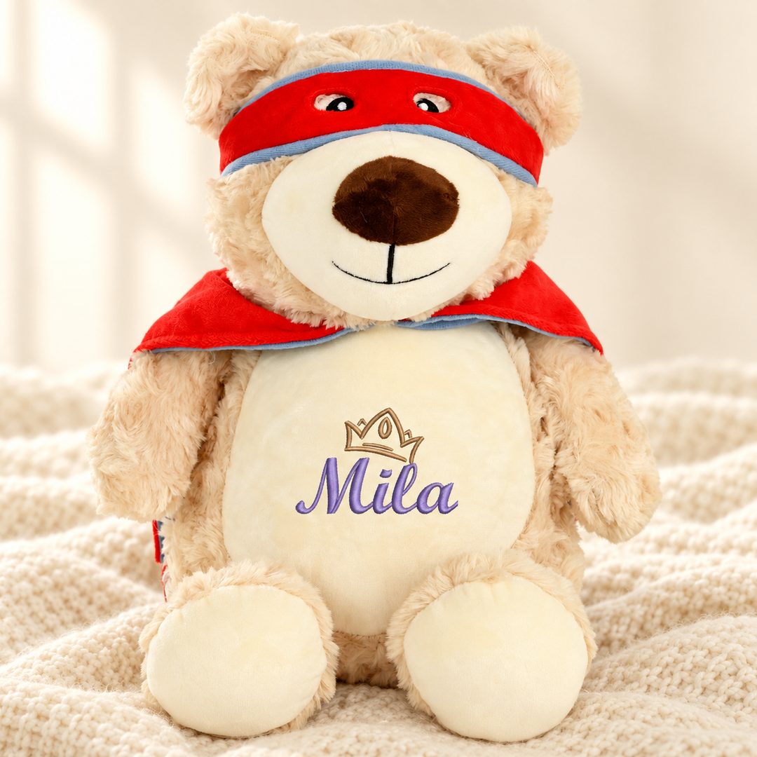 Personalisiertes Kuscheltier Hero Bear mit Name & Krone – Beispiel Mila auf cremefarbener Decke