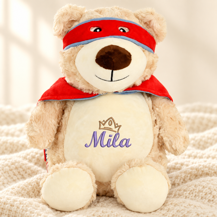 Personalisiertes Kuscheltier Hero Bear mit Name &amp; Krone – Beispiel Mila auf cremefarbener Decke