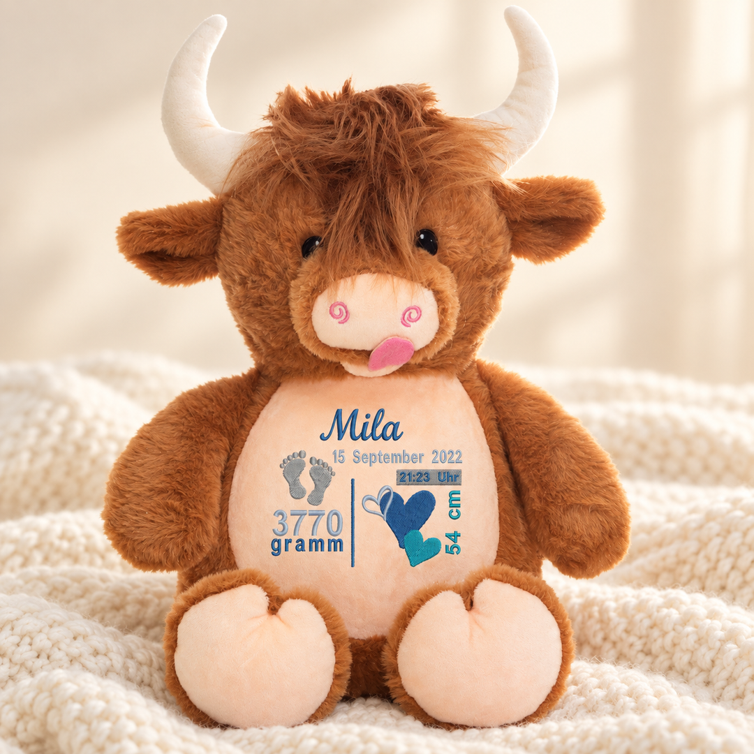 Personalisiertes Kuscheltier Highland-Kuh mit Name & Geburtsdaten – Beispiel Mila auf cremefarbener Decke