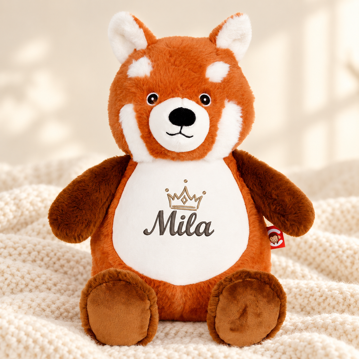 Personalisiertes Kuscheltier Red Panda mit Name – Beispiel Mila auf cremefarbener Decke