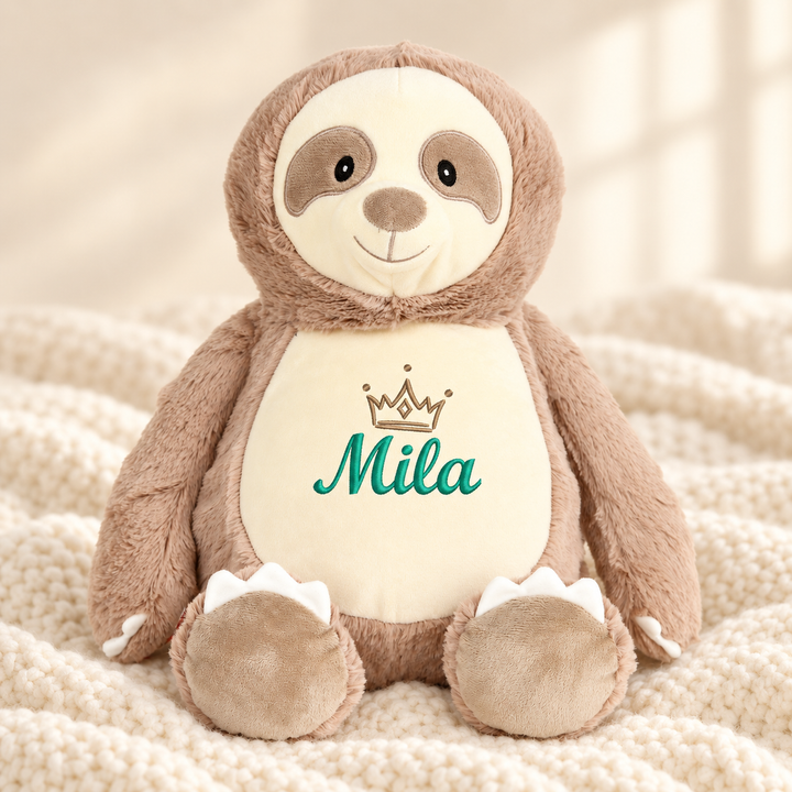 Personalisiertes Kuscheltier Baby Sloth mit Name – Beispiel Mila auf cremefarbener Decke
