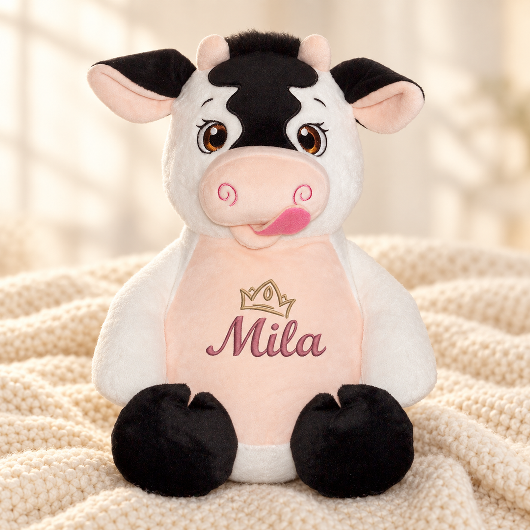 Personalisiertes Kuscheltier Baby Cow mit Name – Beispiel Mila auf cremefarbener Decke