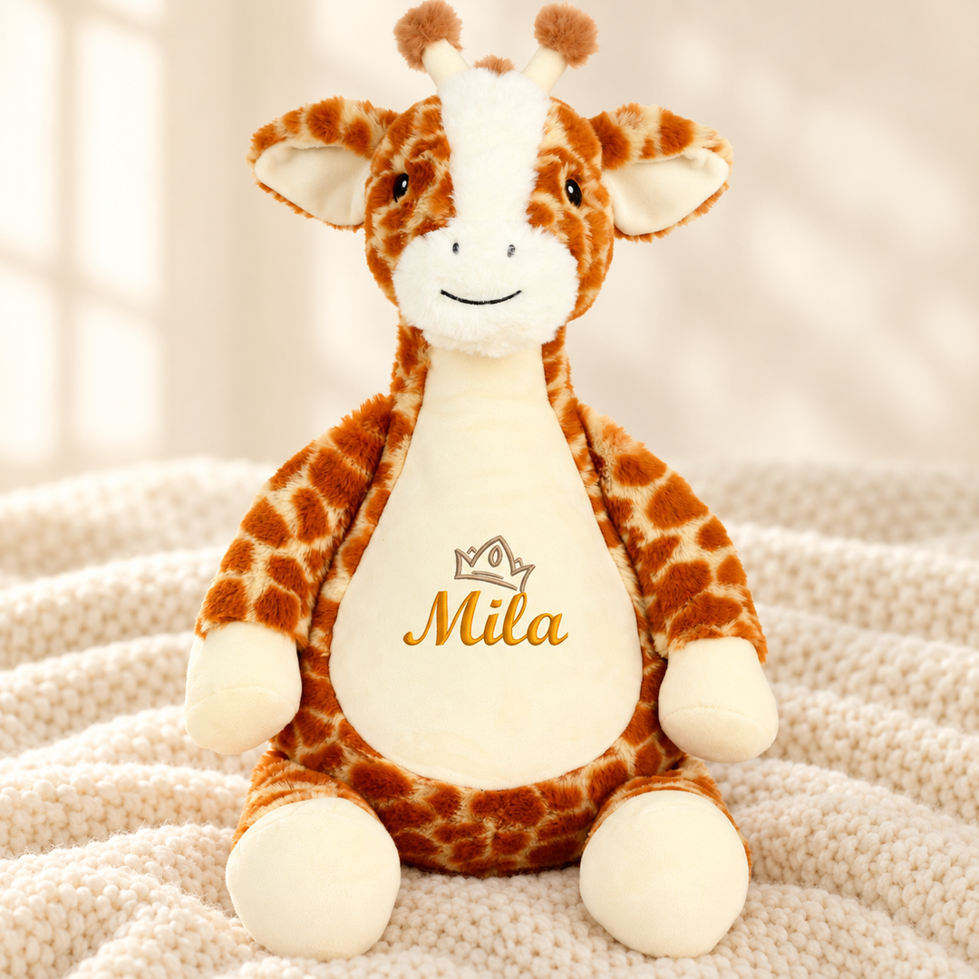 Personalisiertes Kuscheltier Baby Giraffe mit Name – Beispiel Mila auf cremefarbener Decke
