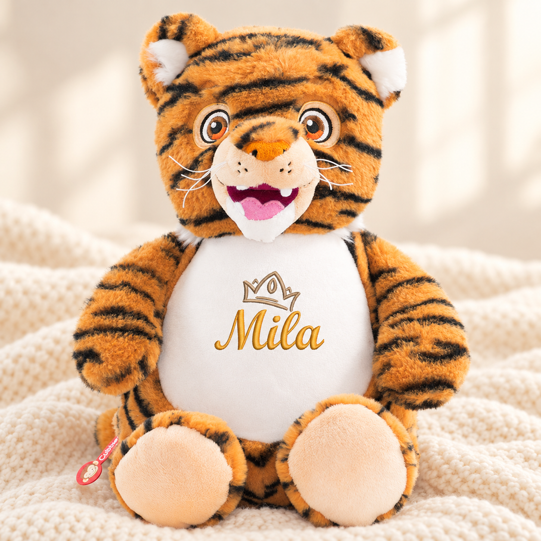 Personalisiertes Kuscheltier Baby Tiger mit Name – Beispiel Mila auf cremefarbener Decke