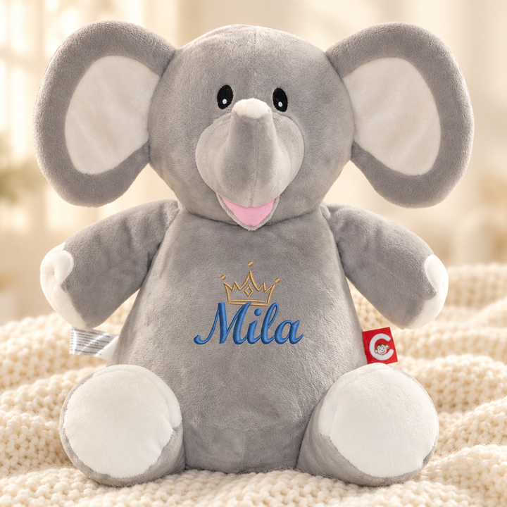Personalisiertes Kuscheltier Grey Elephant mit Name – Beispiel Mila auf cremefarbener Decke
